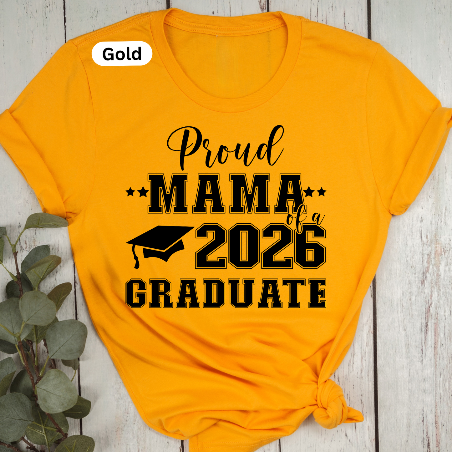 Yellow t-shirt with 'Proud Mama of a 2026 Graduate' text on a wooden surface.  Proud Family Graduate Tee - Senior Class of 2026 Proud Family Senior Shirt
