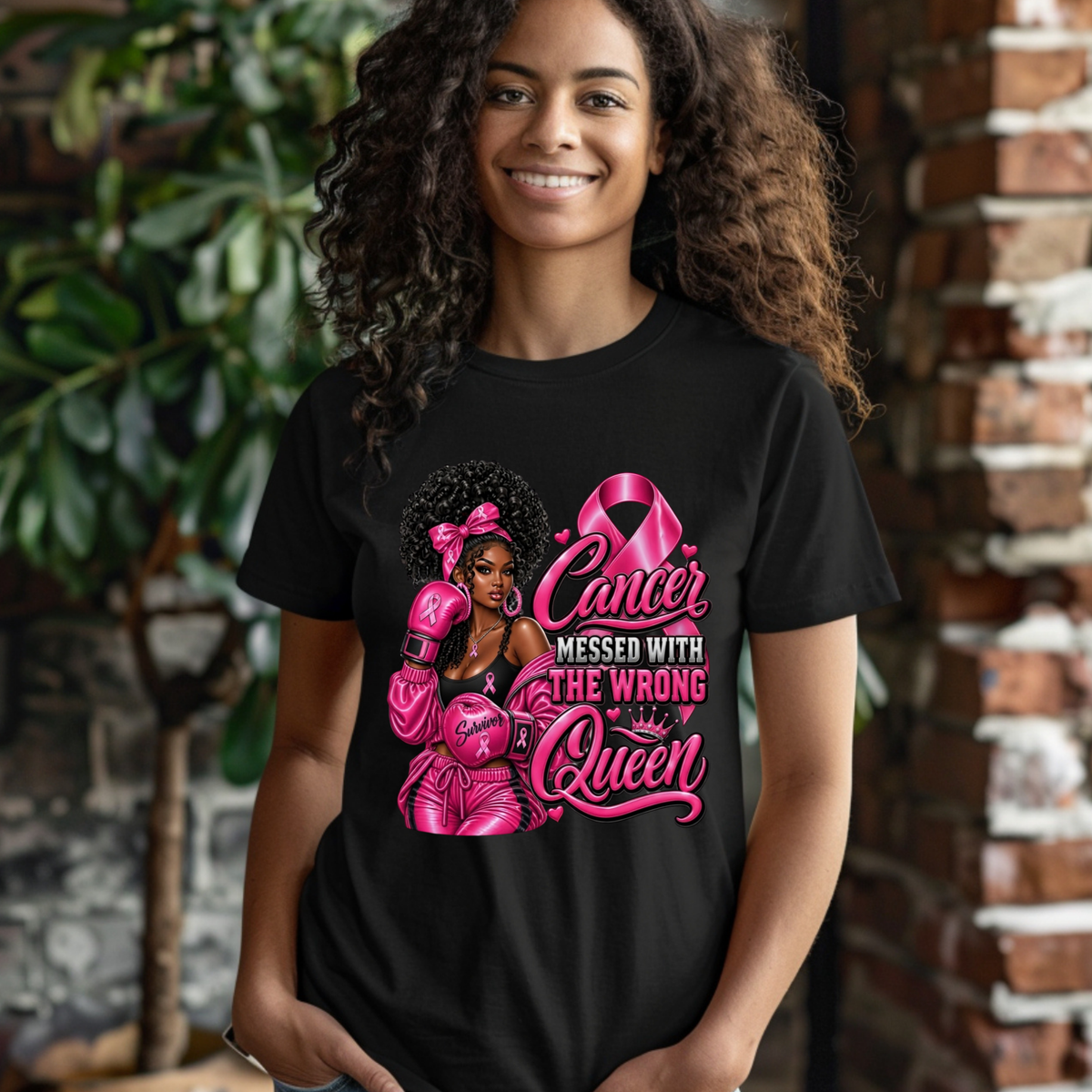 A smiling woman with curly hair wearing a black graphic t-shirt. The shirt features a pink ribbon design and the text 'HER Fight IS OUR Fight' in pink and white, alongside portraits of three women.