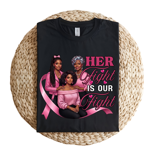 A black short-sleeve T-shirt laid flat on a round woven straw mat, featuring a large pink and white graphic that reads “I AM A SURVIVOR” with pink awareness ribbons, butterflies, and hearts.