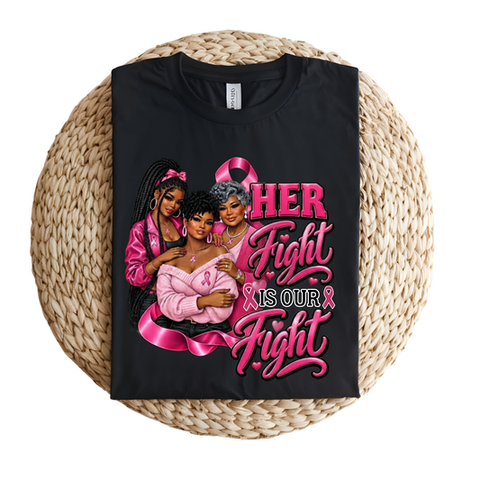 A black short-sleeve T-shirt laid flat on a round woven straw mat, featuring a large pink and multicolored graphic with three women and the text 'HER Fight IS OUR Fight' with pink awareness ribbons.