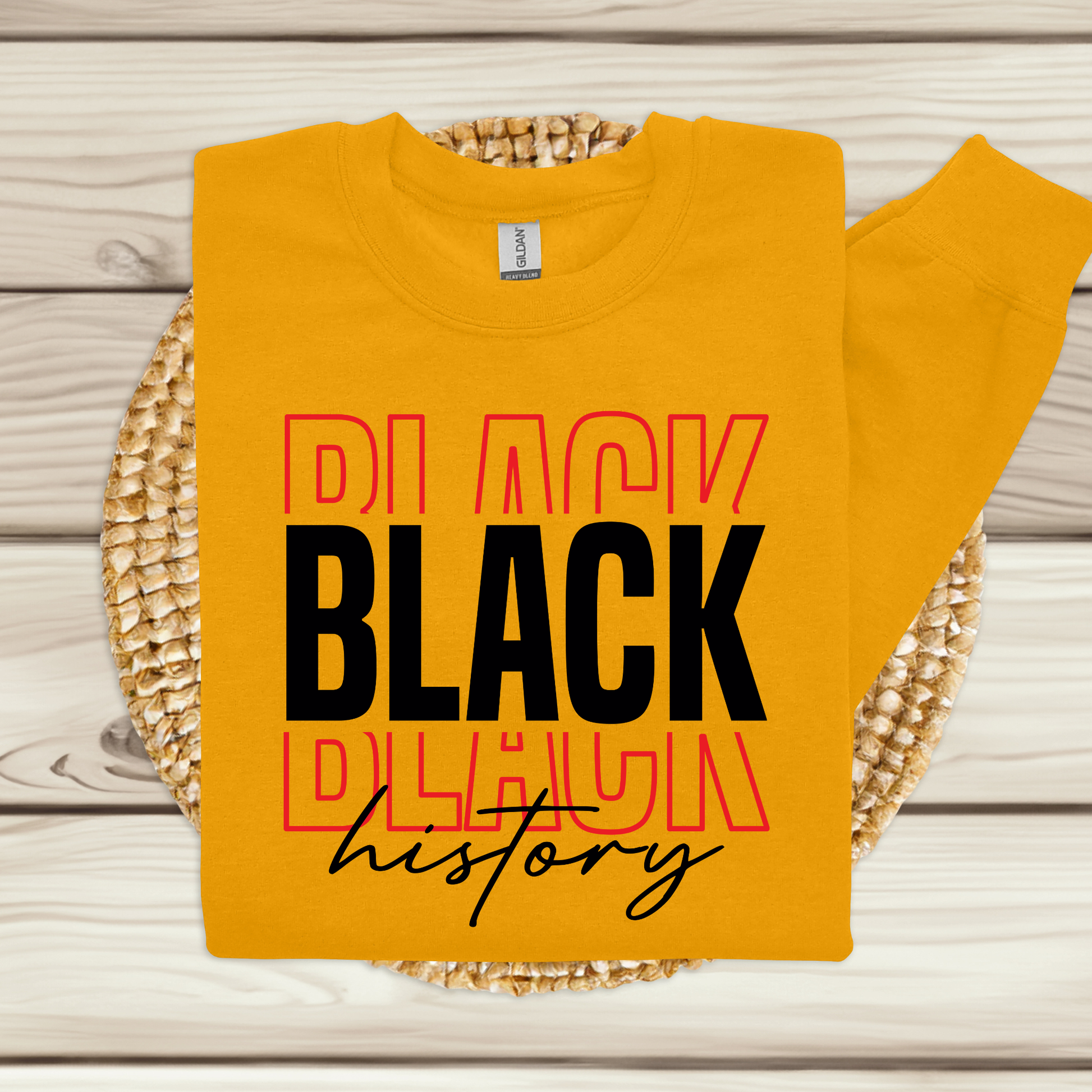 Yellow sweatshirt with 'BLACK HISTORY' text on a wooden surface