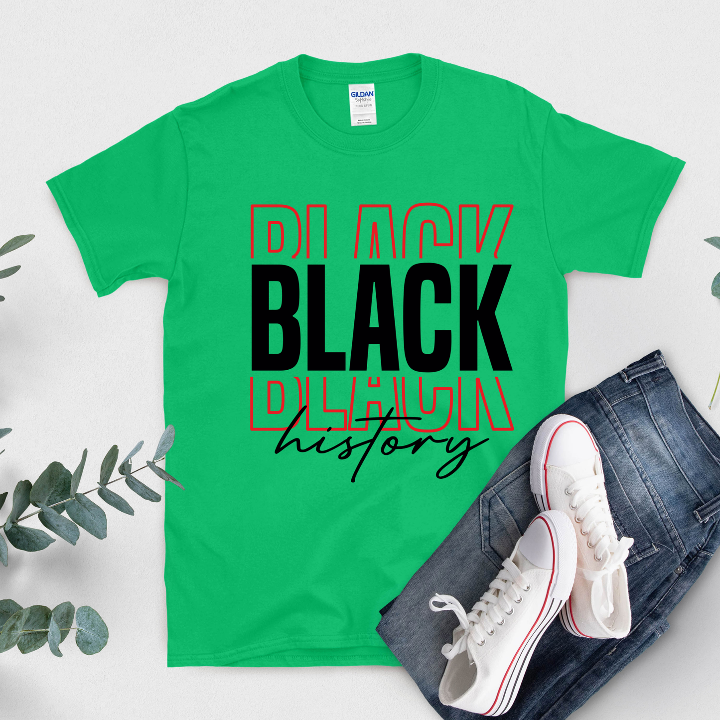 Green t-shirt with 'Black History' text, white sneakers, and jeans on a light background
