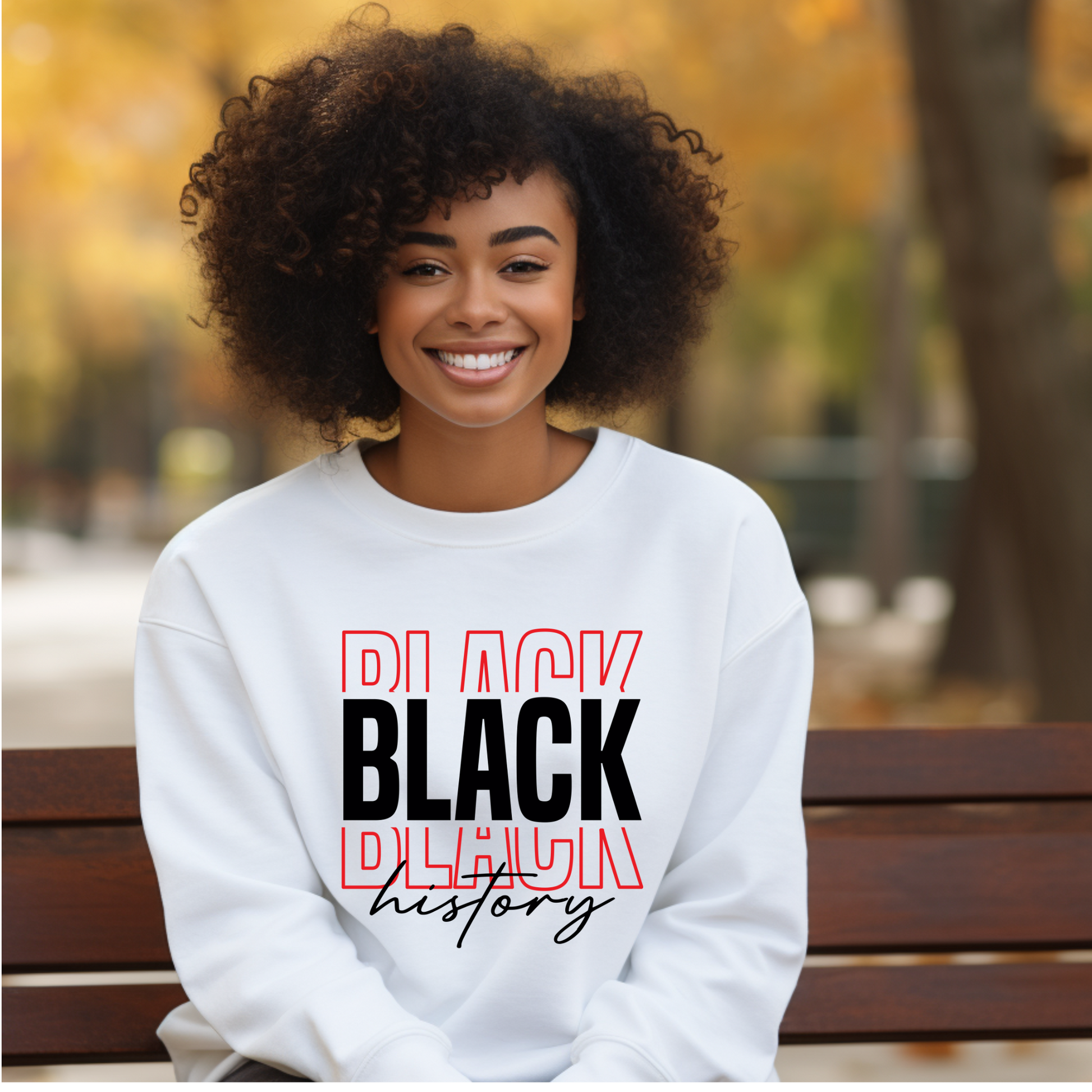 Woman wearing a white sweatshirt with 'Black History' text, sitting on a bench outdoors.