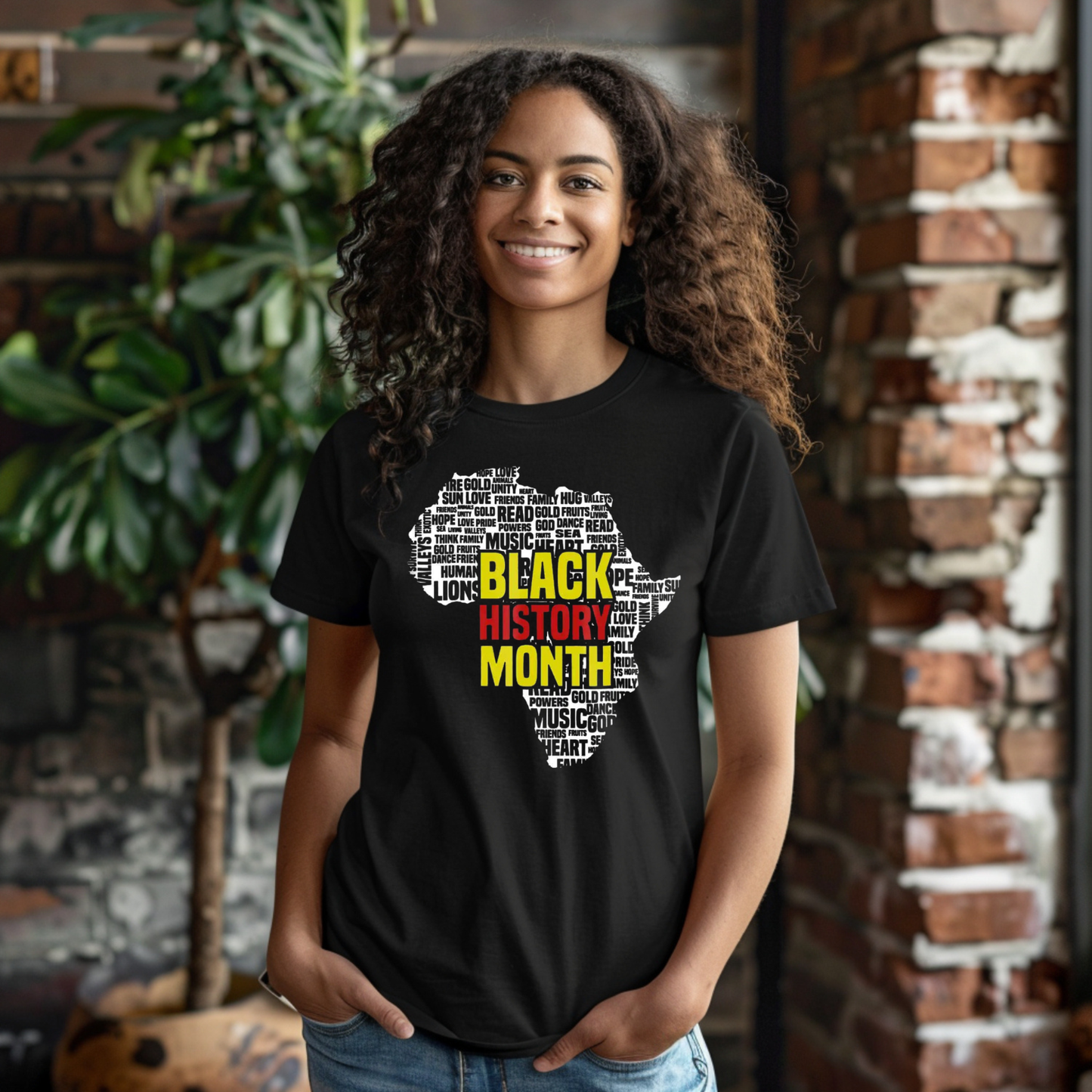 Person wearing a black t-shirt with 'Black History Month' design, standing against a brick wall.