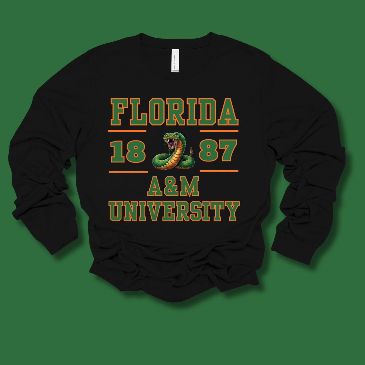 A black long-sleeve crewneck sweatshirt featuring a graphic print for 'Florida 1887 A&M University' in green and orange lettering with a snake illustration, displayed on a solid green background.