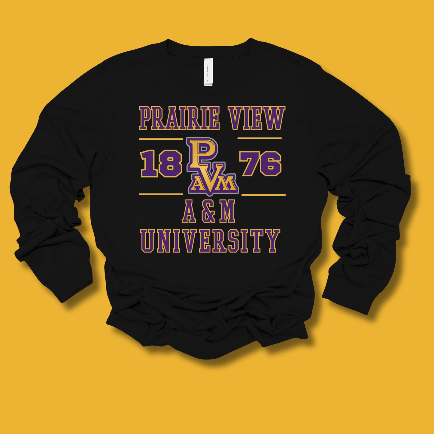 A black long-sleeve crewneck sweatshirt with a graphic print on the front reading 'PRAIRIE VIEW 18 PV 76 A&M UNIVERSITY' in purple and gold, laid flat against a solid mustard yellow background.