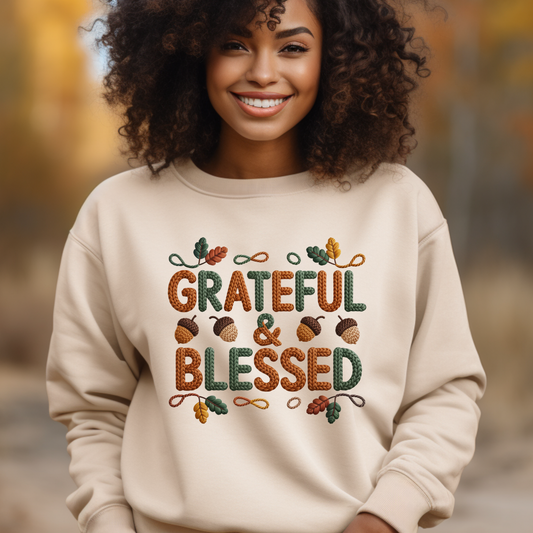 Woman wearing a beige sweatshirt with 'Grateful & Blessed' text and autumn-themed design outdoors.