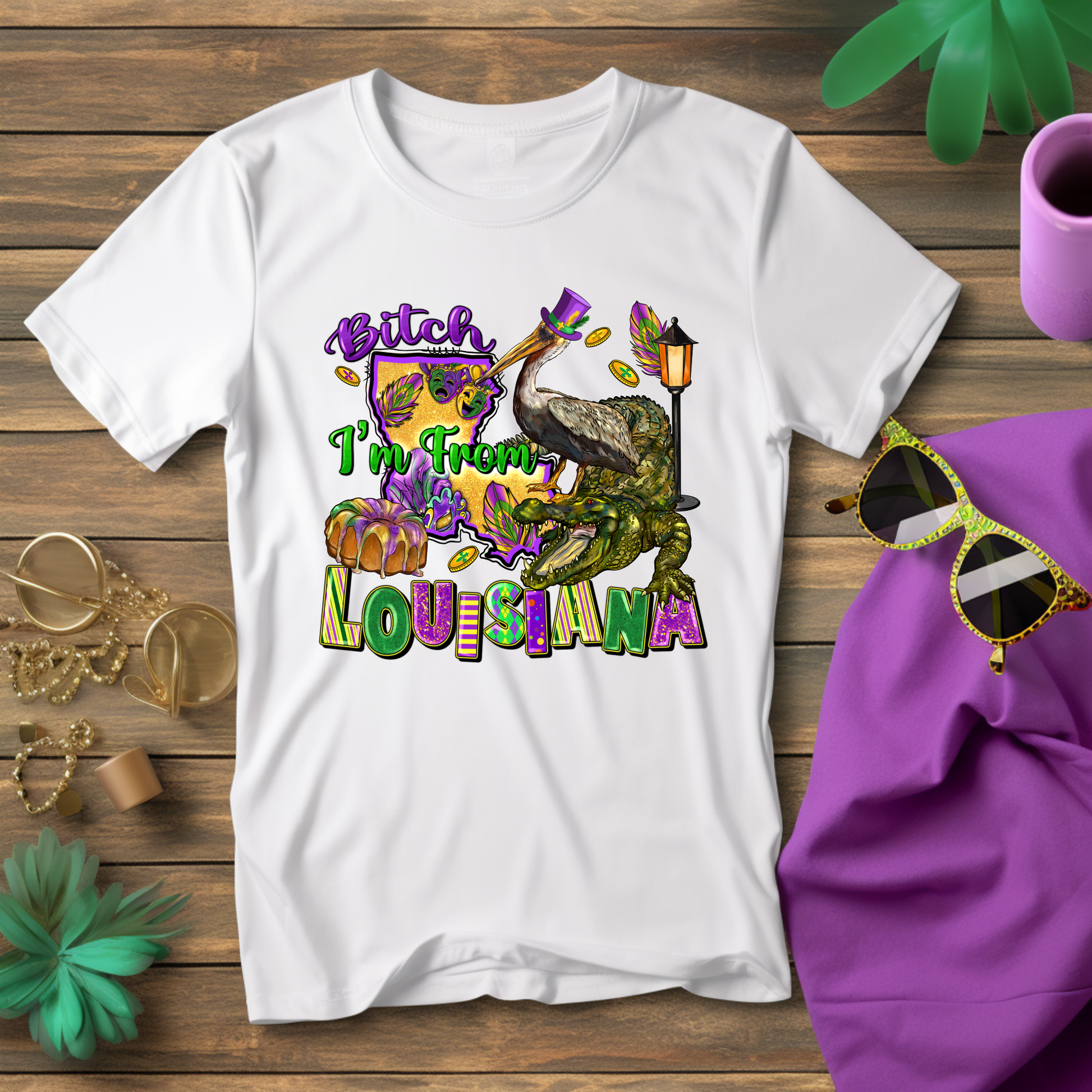 White t-shirt with colorful graphic and text on a wooden surface with accessories.