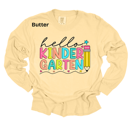A pale butter-yellow long-sleeve t-shirt with a colorful graphic reading 'hello KINDER GARTEN' and a pencil illustration. The word 'Butter' is printed in black near the upper left chest, indicating the fabric color.