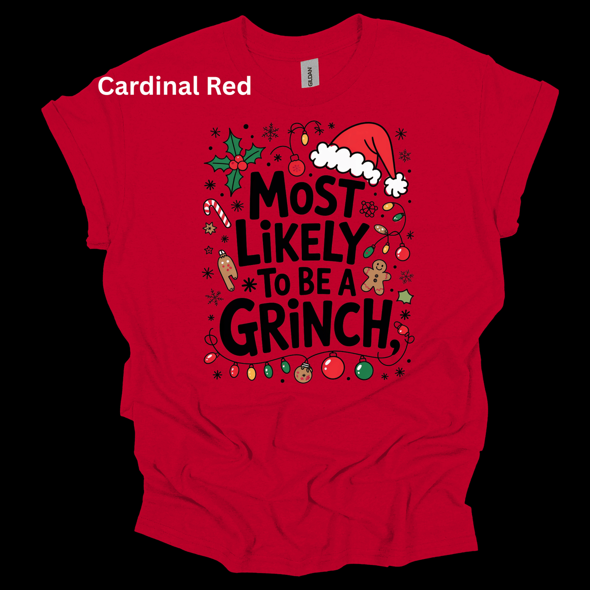 A red short-sleeve t-shirt with a festive Christmas graphic that reads 'MOST LIKELY TO BE A GRINCH' in black text, surrounded by holiday illustrations like a Santa hat, holly, candy canes, and gingerbread cookies. The text 'Cardinal Red' is written in white in the upper left corner.