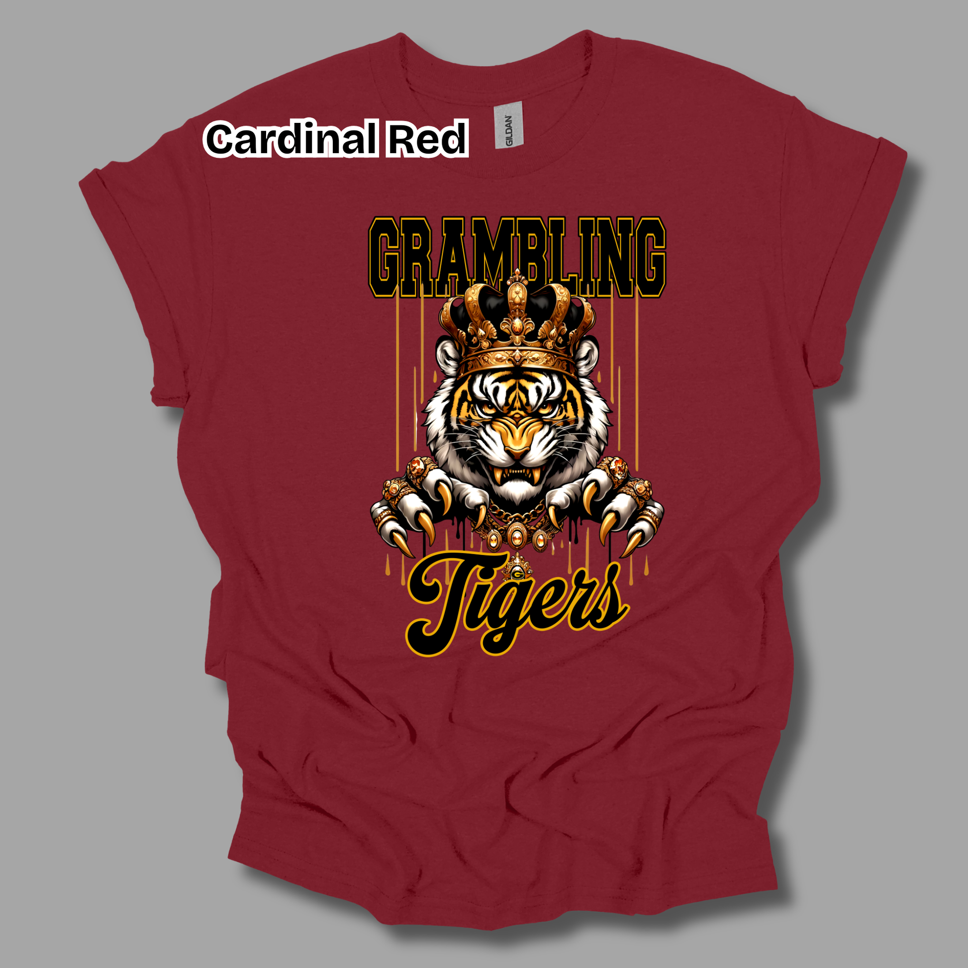A maroon short-sleeve t-shirt with a graphic of a tiger wearing a gold crown and the text 'GRAMBLING Tigers'. A white label at the collar reads 'Cardinal Red'.