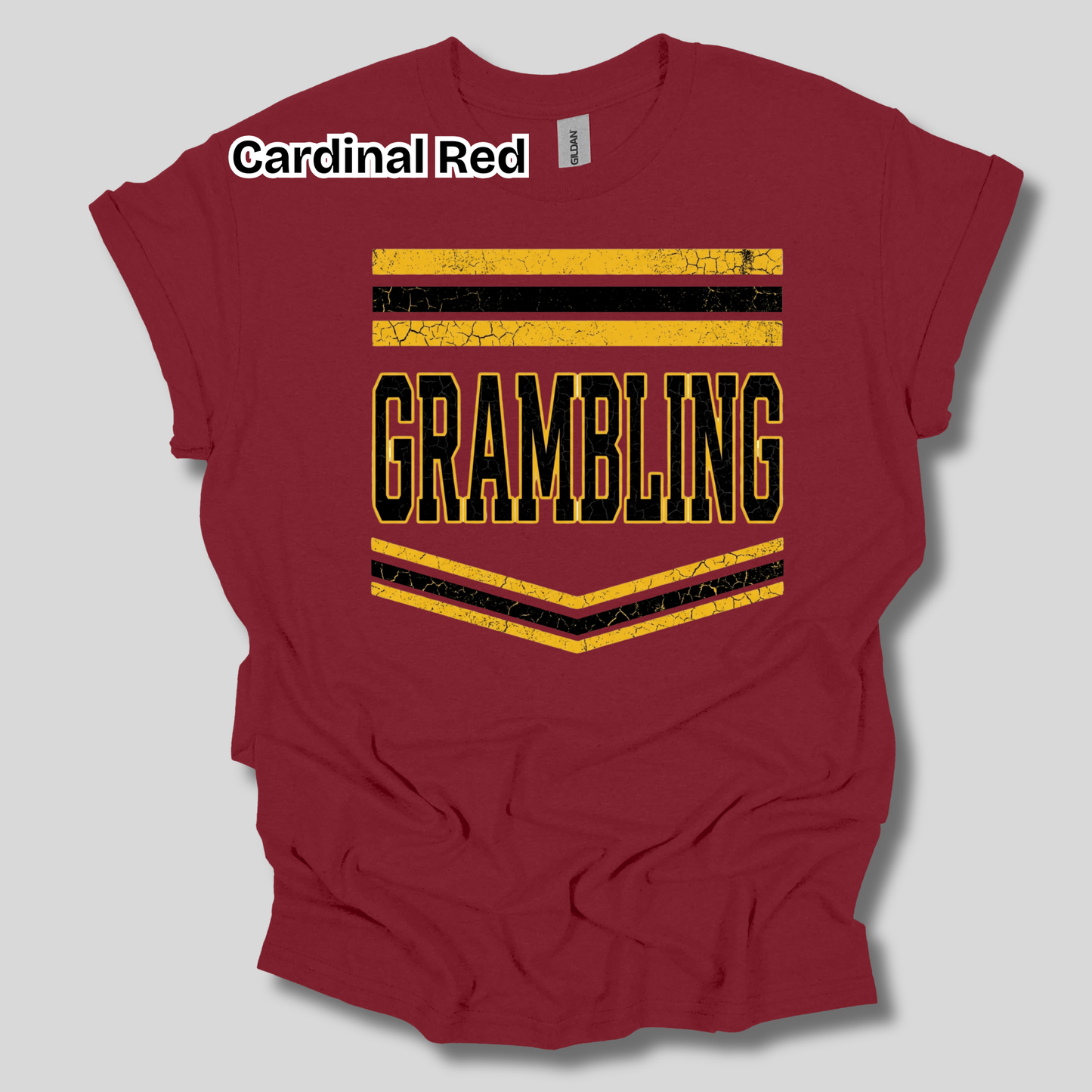 A maroon short-sleeve t-shirt with a distressed graphic that reads 'GRAMBLING' in black letters outlined in yellow, framed by yellow and black stripes. A white text label at the top left reads 'Cardinal Red'.
