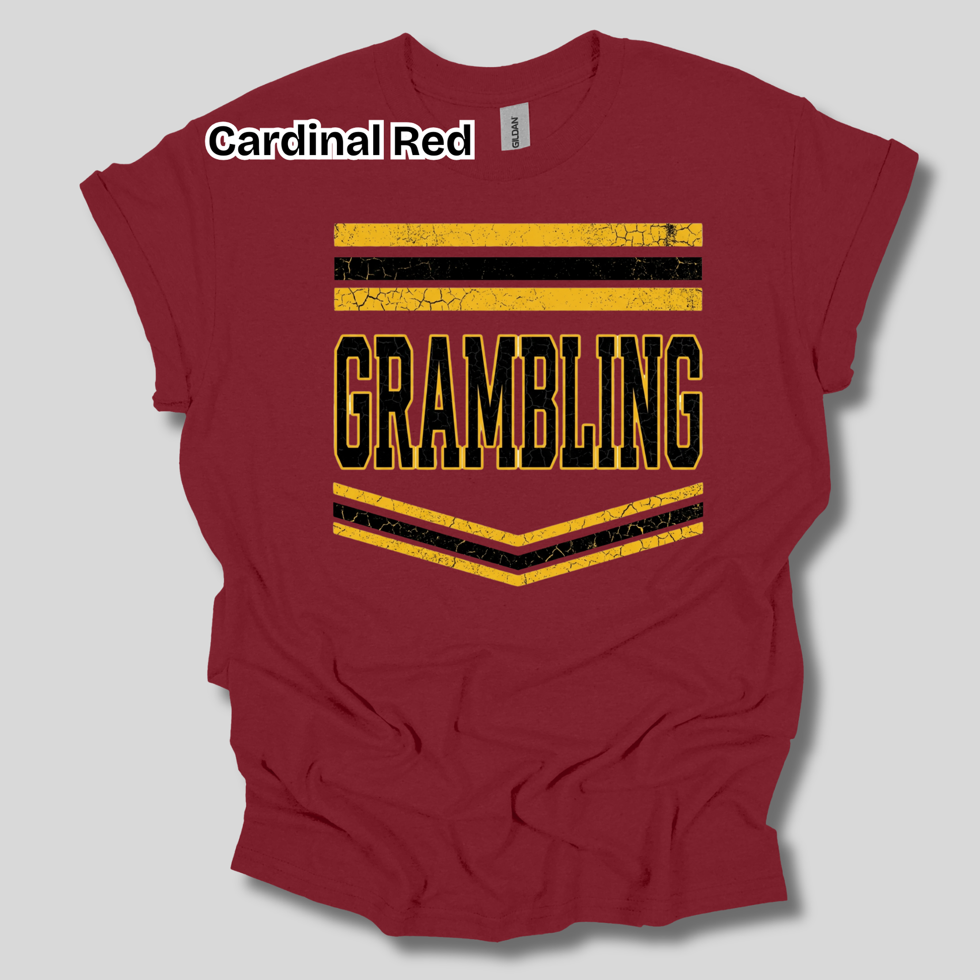 A maroon short-sleeve t-shirt with a distressed graphic that reads 'GRAMBLING' in black letters outlined in yellow, framed by yellow and black stripes. A white text label at the top left reads 'Cardinal Red'.
