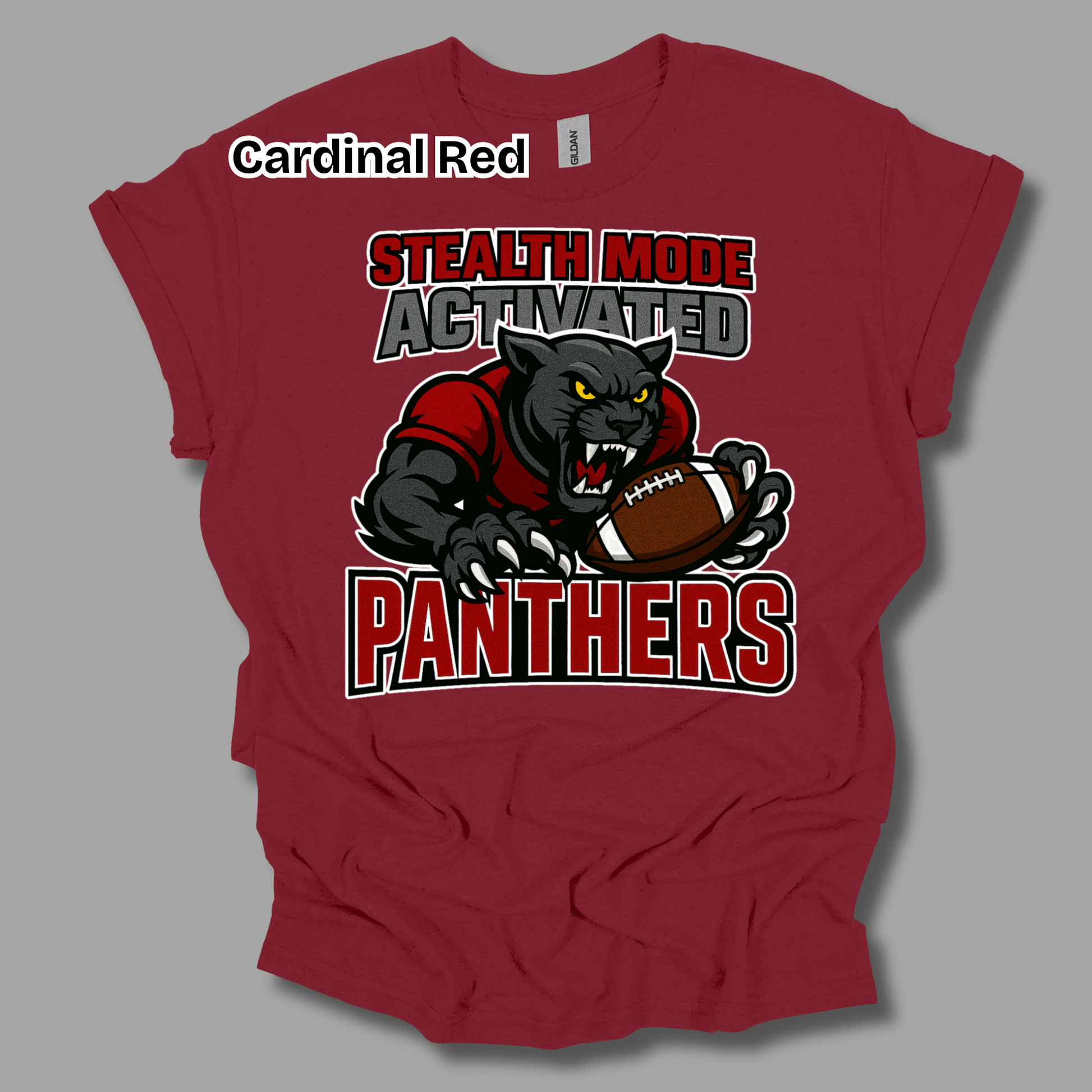 A red short-sleeve t-shirt with a graphic of a black panther holding a football, with the text 'STEALTH MODE ACTIVATED PANTHERS' in red, white, and gray. The shirt is shown on a gray background with a 'Cardinal Red' label overlay.