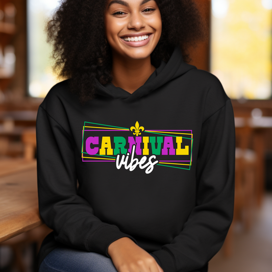 Person wearing a black hoodie with 'Carnival vibes' text in bright colors, sitting indoors.