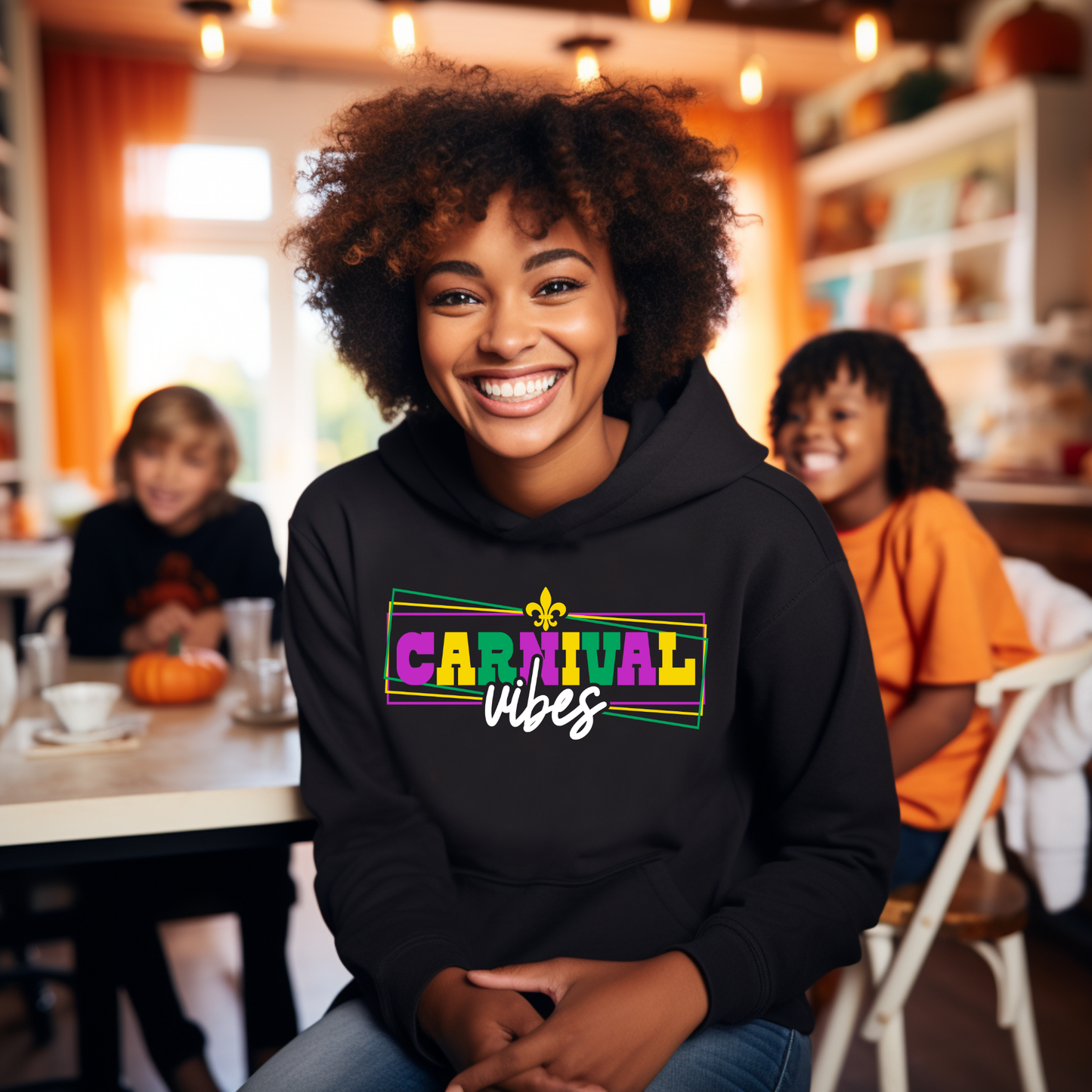 Person wearing a black hoodie with 'Carnival vibes' text, sitting in a casual indoor setting.