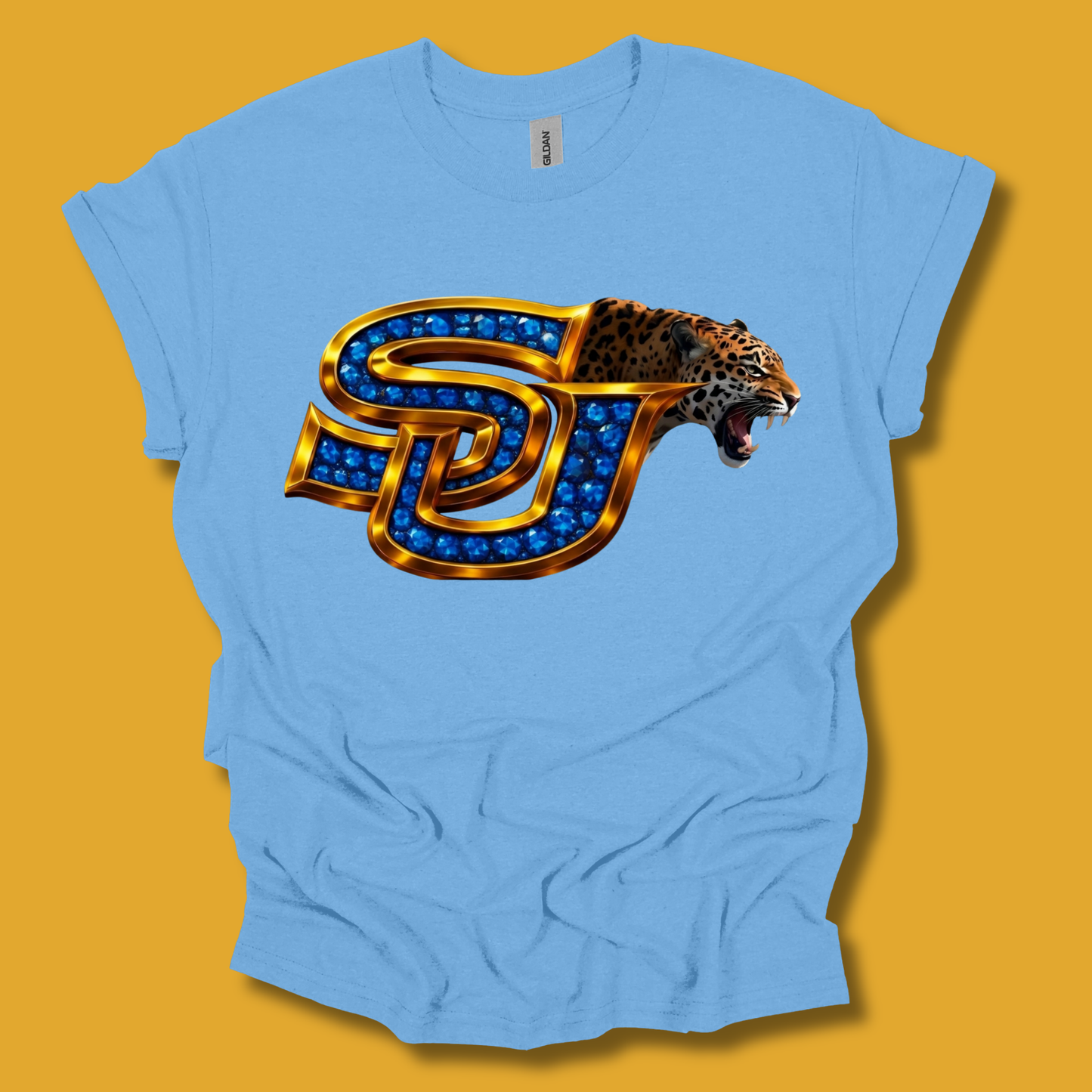 A light blue short-sleeve t-shirt with a graphic of a roaring leopard head integrated into a stylized interlocking 'SD' monogram filled with blue gem-like details, set against a solid mustard yellow background.