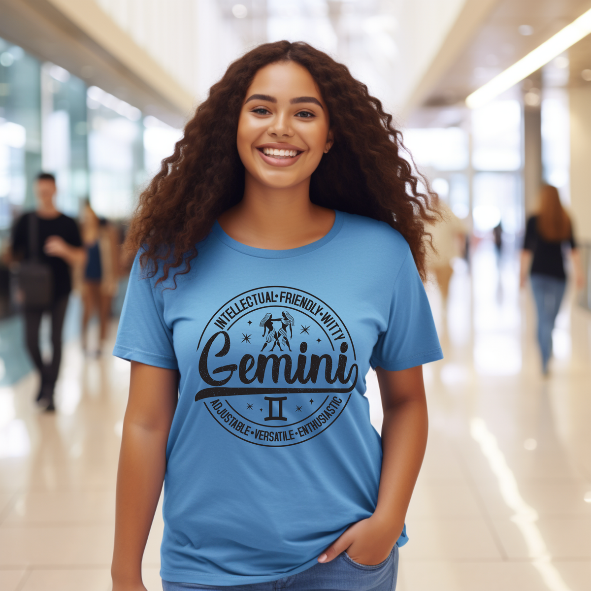 blue t-shirt laid flat, featuring a circular white Gemini zodiac graphic with the twins illustration, the word "Gemini," and trait keywords like intellectual, friendly, witty, enthusiastic, versatile, and adjustable.