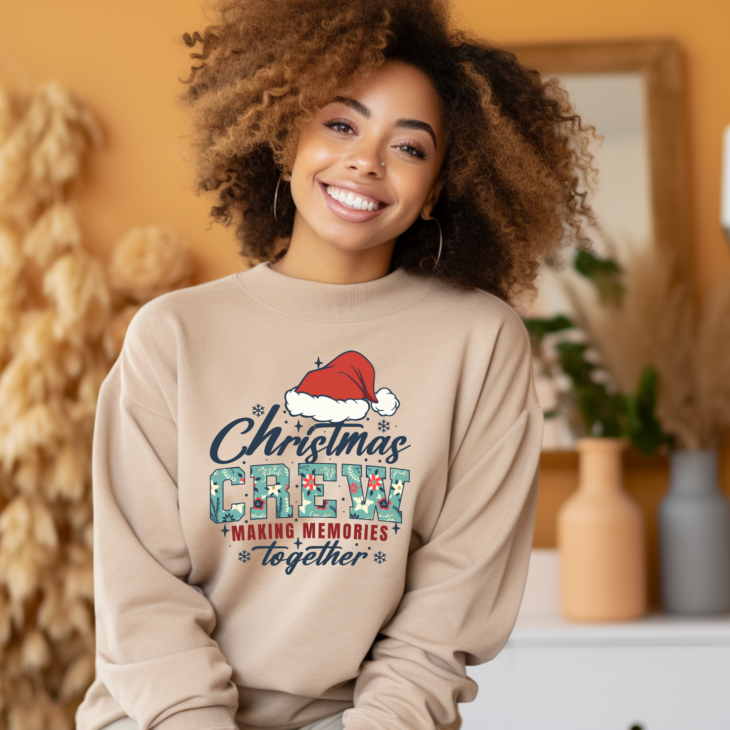 Woman wearing a beige sweatshirt with Christmas Crew design in a warm indoor setting