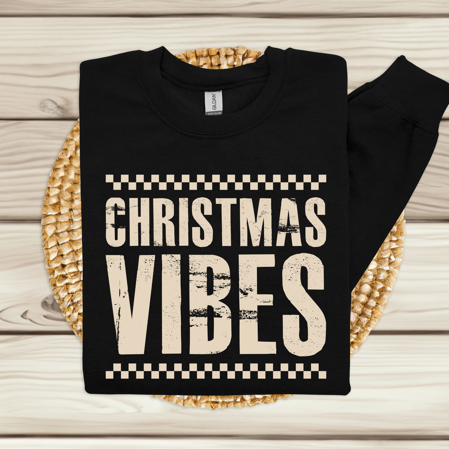 Black sweatshirt with 'Christmas Vibes' text on a woven mat