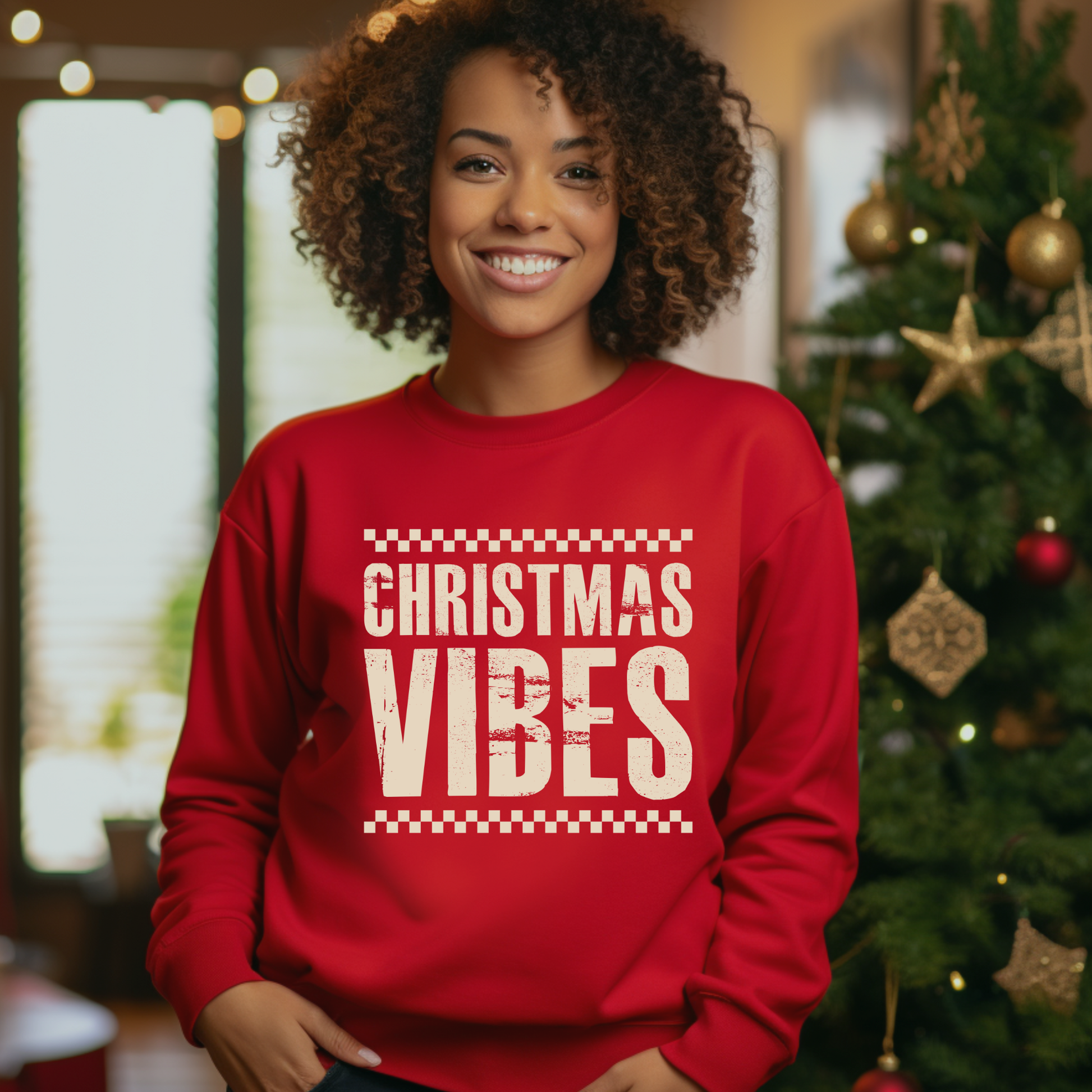 Person wearing a red sweatshirt with 'Christmas Vibes' text in a festive setting with a Christmas tree.