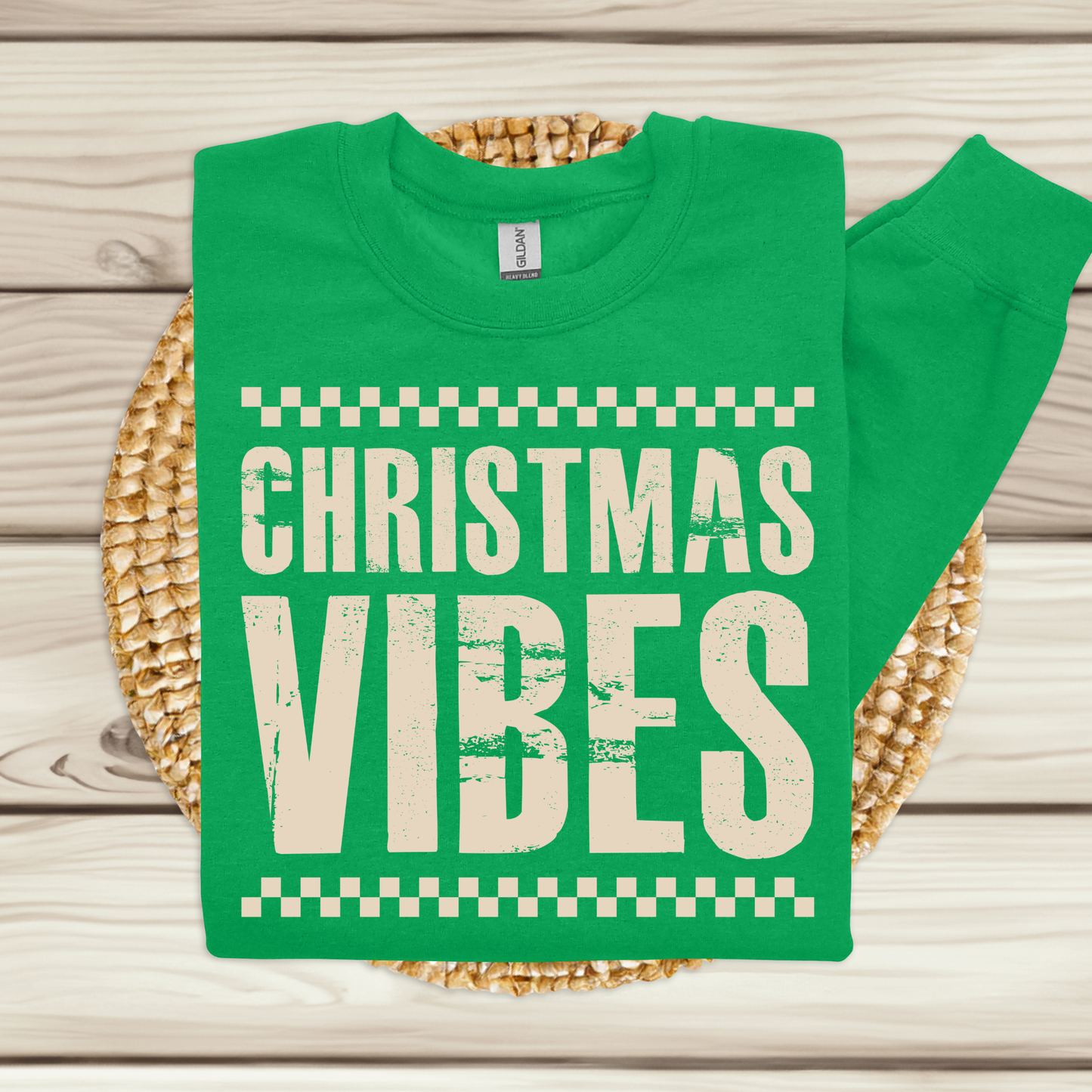Green t-shirt with 'Christmas Vibes' text on a woven mat