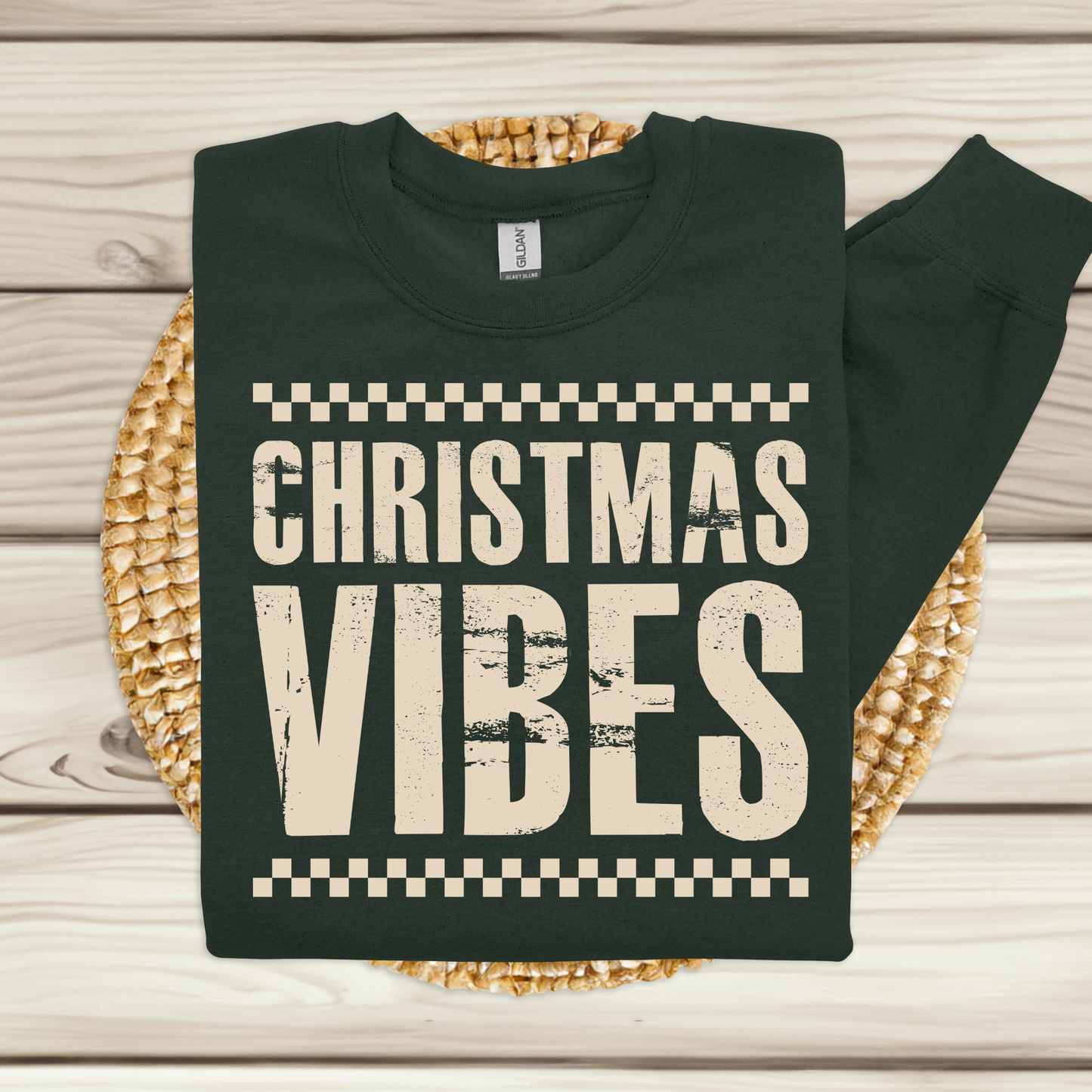 Black sweatshirt with 'Christmas Vibes' text on a woven mat