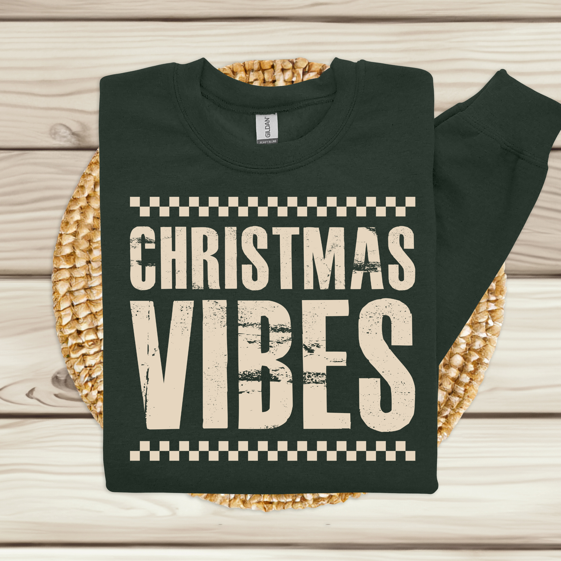 Black sweatshirt with 'Christmas Vibes' text on a woven mat