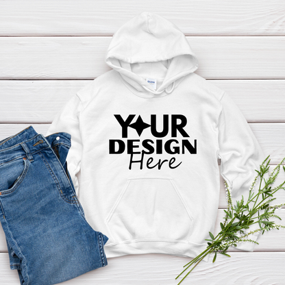 White hoodie with 'Your Design Here' text on a wooden surface with jeans and plants.