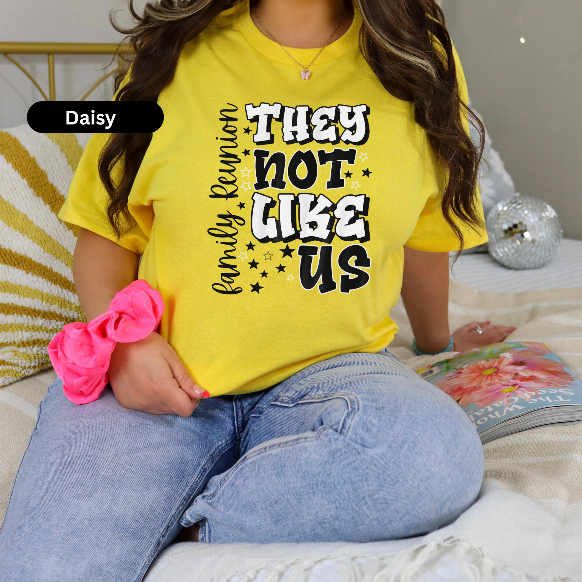 Person wearing a yellow t-shirt with text, sitting on a bed.
