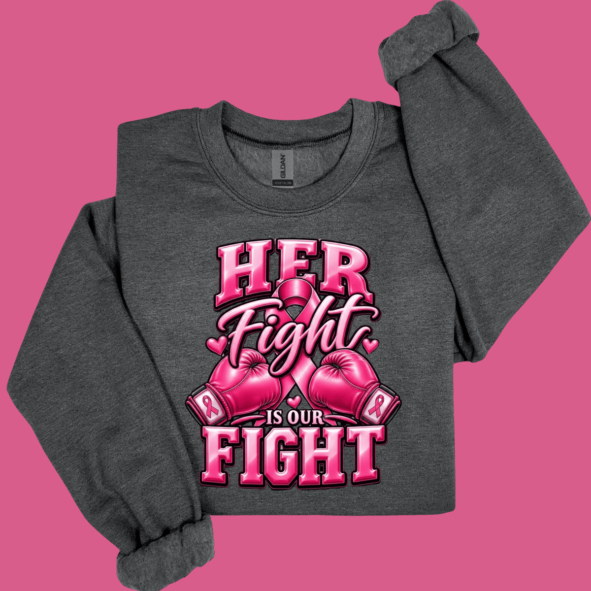 A dark heather gray long-sleeve t-shirt with a pink graphic print that reads 'HER Fight IS OUR FIGHT' with pink boxing gloves and a ribbon motif, displayed on a solid pink background.