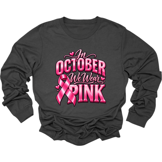 A dark charcoal gray long-sleeve t-shirt with a pink graphic on the front that reads 'In October We Wear Pink' alongside a pink ribbon design, displayed on a clean white background.