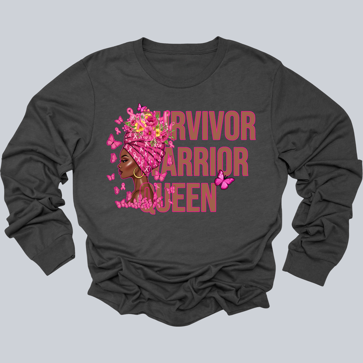 A dark charcoal gray long-sleeve t-shirt with a graphic print on the front. The graphic features the words 'SURVIVOR WARRIOR QUEEN' in a dusty pink font, layered with an illustration of a Black woman with pink hair accessories and butterflies.