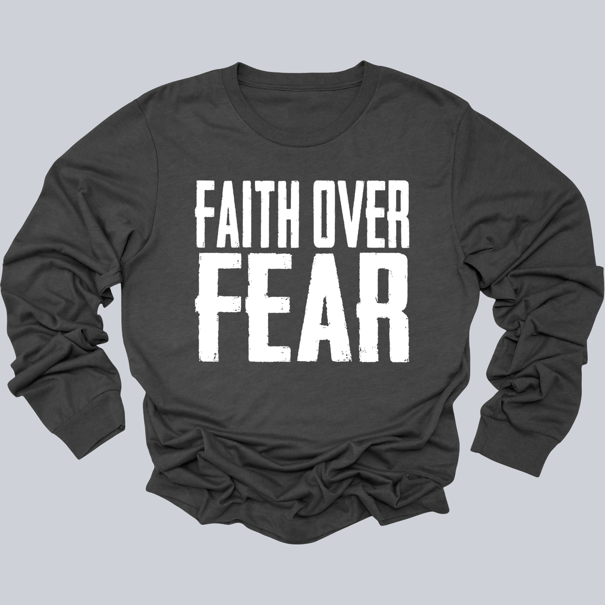 A dark charcoal gray long-sleeve t-shirt with the phrase 'FAITH OVER FEAR' printed in large, distressed white block letters across the chest, displayed on a solid light gray background.