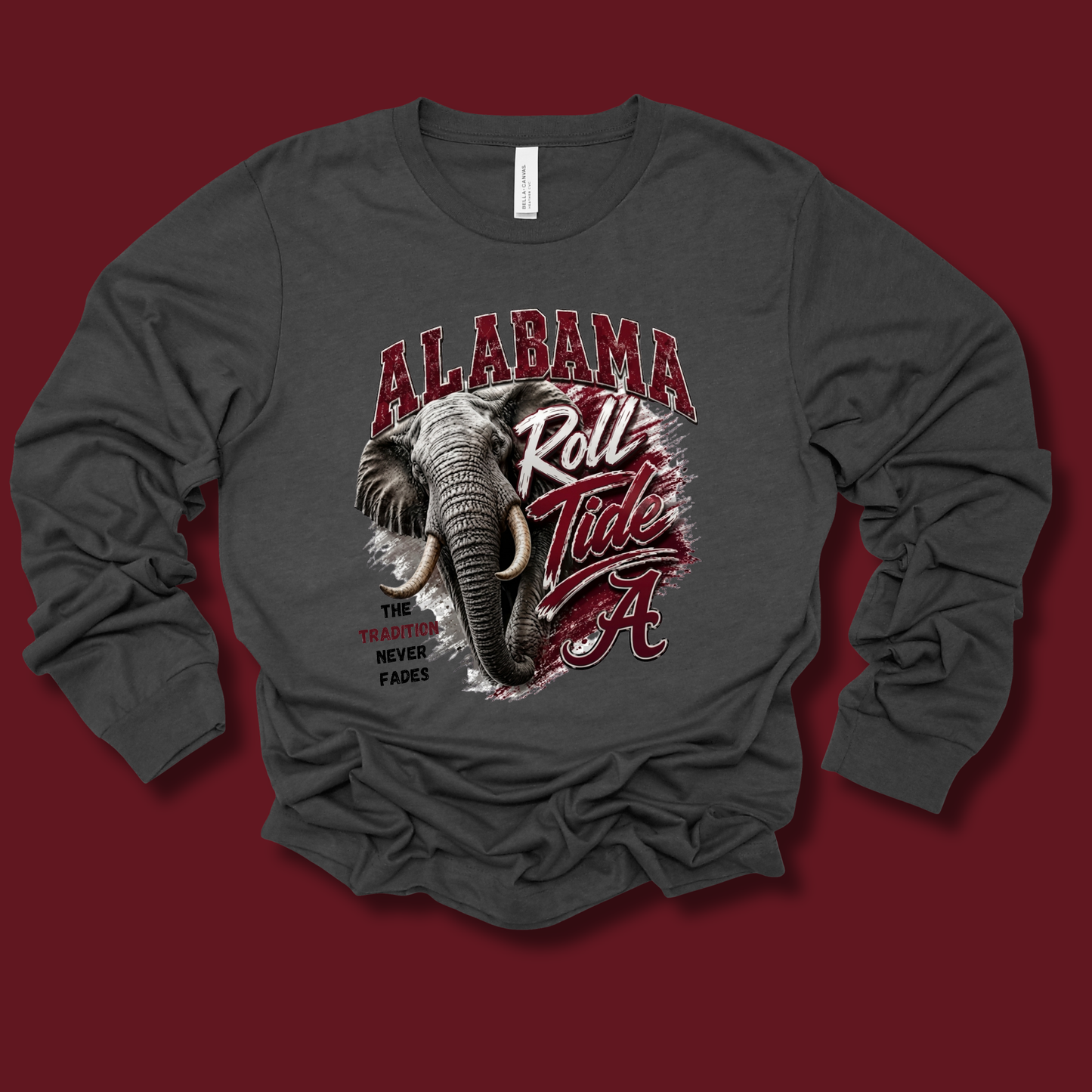 A dark gray long-sleeve t-shirt with a graphic print of an elephant and the text 'ALABAMA Roll Tide' in red and white, displayed on a solid dark red background.