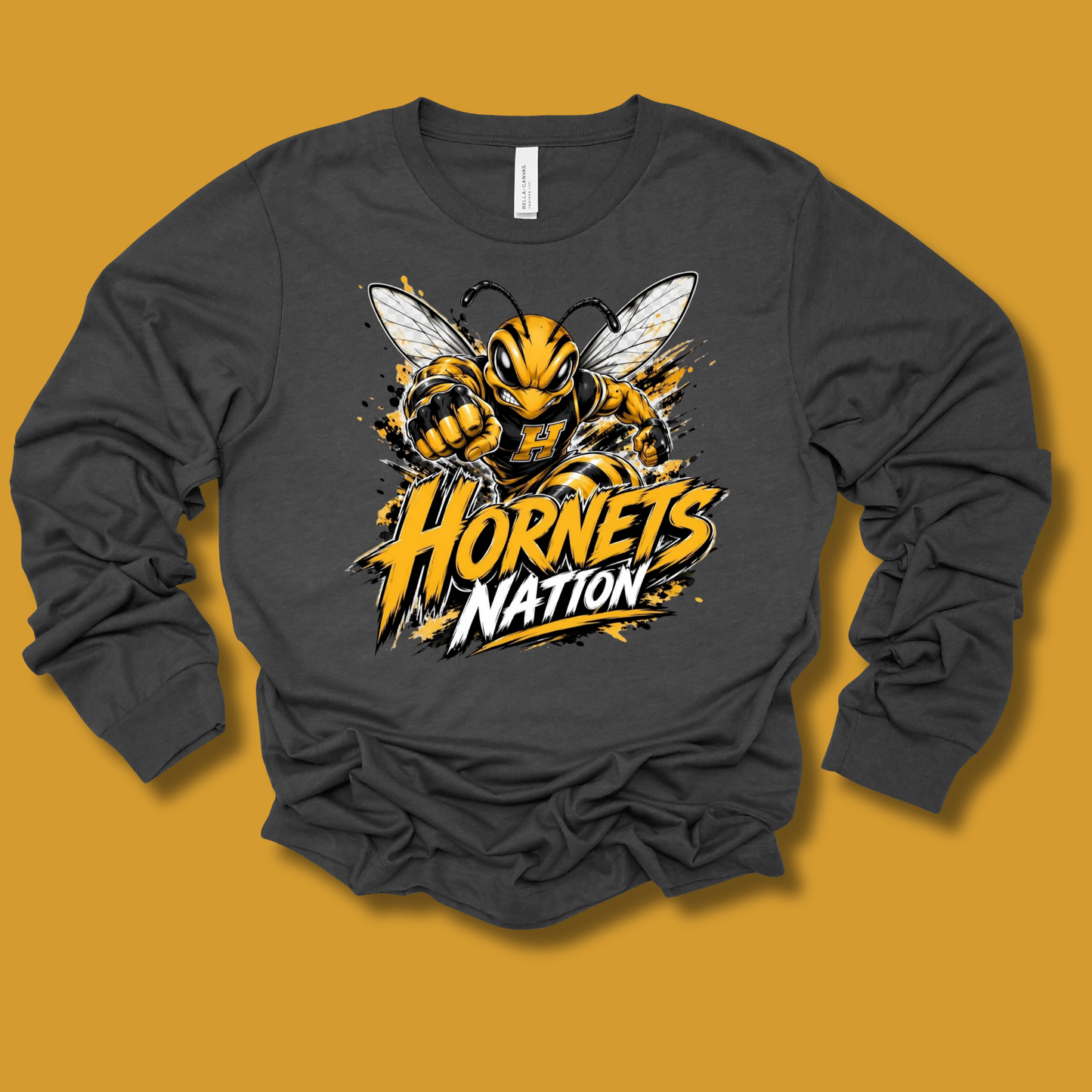 A dark gray long-sleeve t-shirt with a graphic of a yellow and black hornet and the text 'Hornets Nation' on the front, displayed against a solid mustard yellow background.