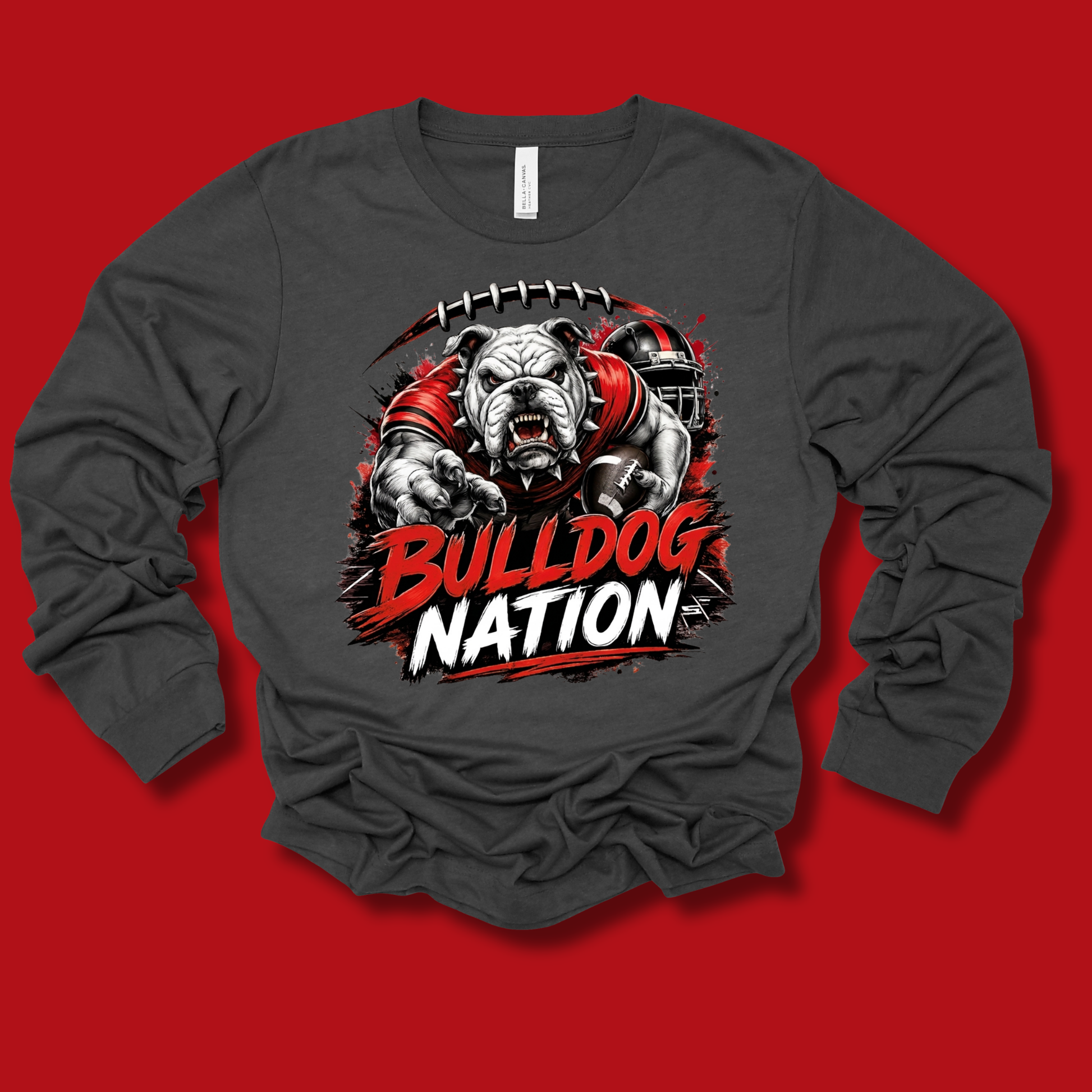 A dark gray long-sleeve t-shirt with a graphic of a bulldog mascot wearing a red jersey, with the text 'BULLDOG NATION' in red and white. The shirt is displayed flat against a solid red background.
