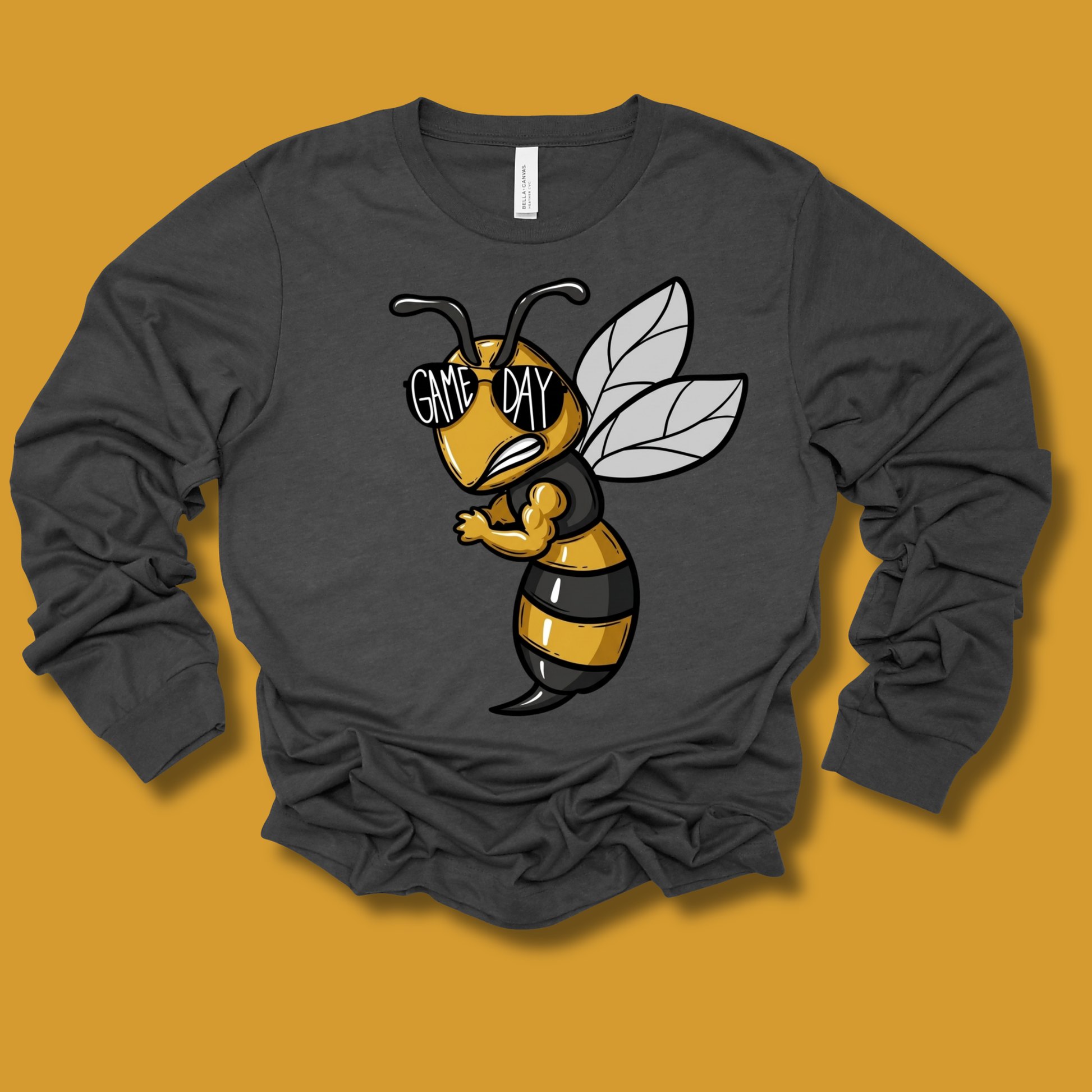 A dark gray long-sleeve t-shirt with a cartoon bee graphic on the front, displayed flat against a solid mustard yellow background.