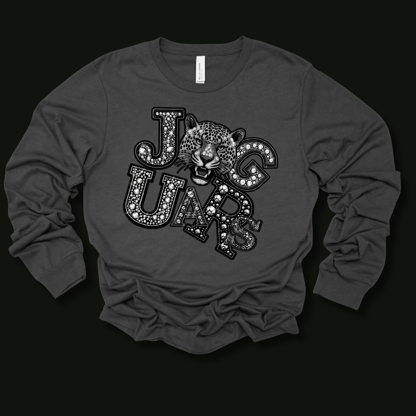 A dark gray long-sleeve t-shirt with a graphic print of the word 'JAGUARS' in a patterned font, featuring a jaguar head in the center, displayed on a solid black background.