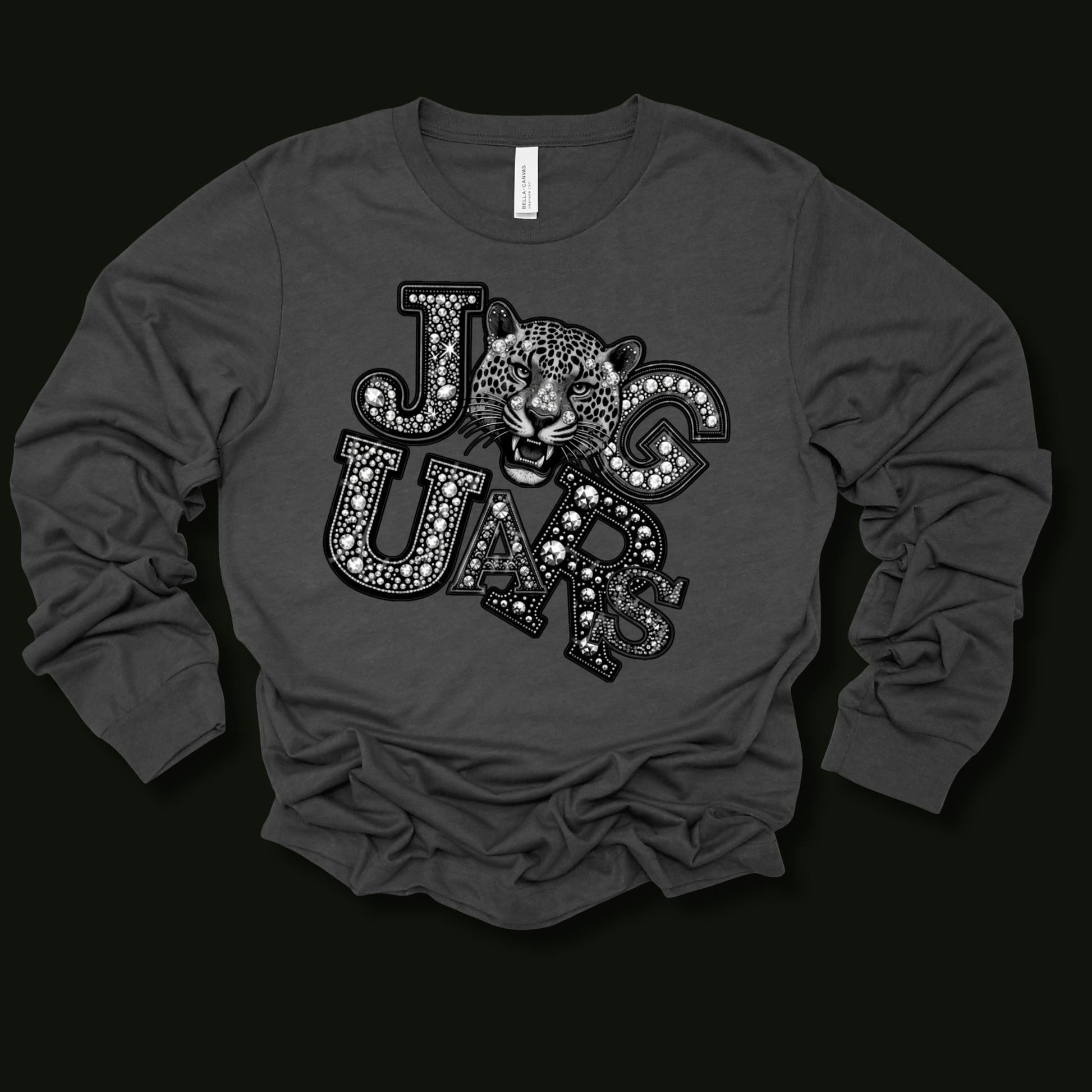 A dark gray long-sleeve t-shirt with a graphic print of the word 'JAGUARS' in a patterned font, featuring a jaguar head in the center, displayed on a solid black background.
