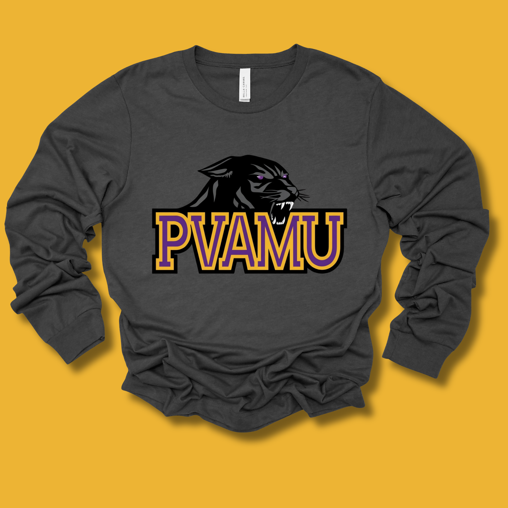 A dark gray long-sleeve t-shirt with a 'PVAMU' athletic graphic featuring a black panther head and the letters 'PVAMU' in purple and gold, laid flat on a solid yellow background.