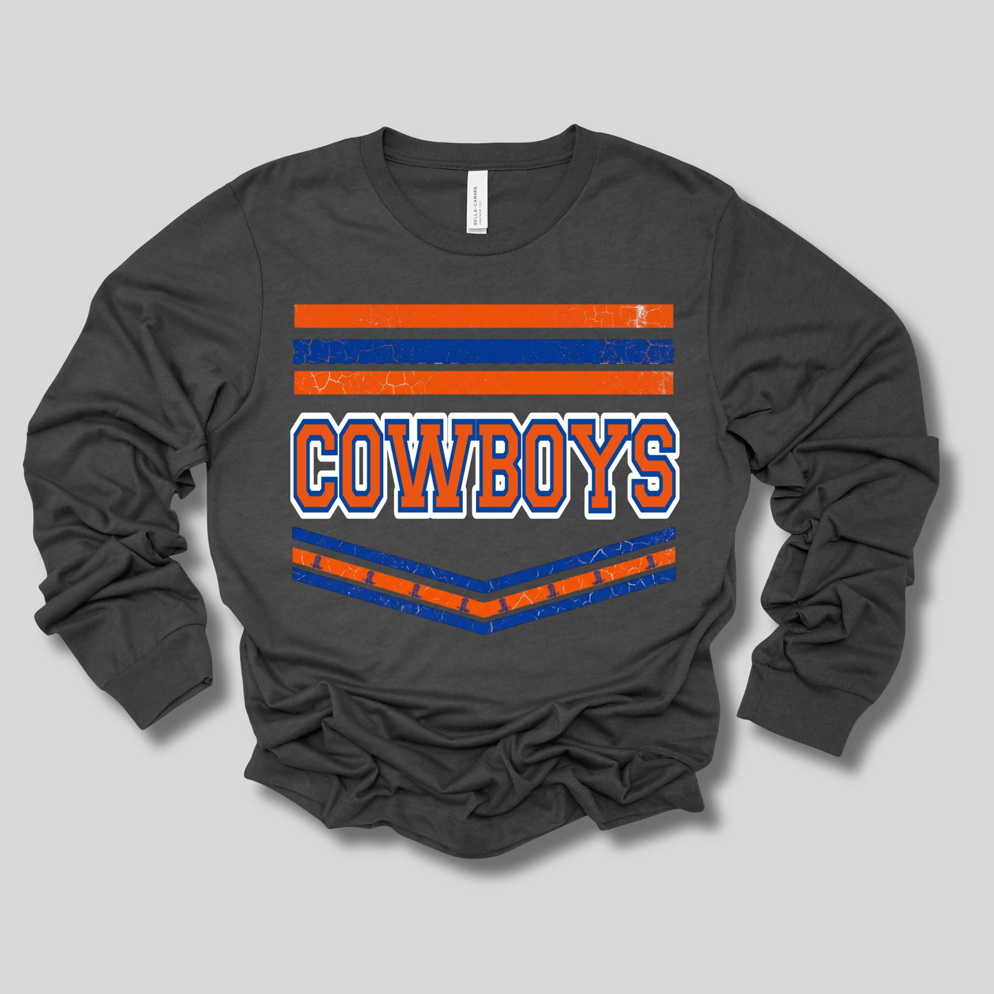A dark charcoal gray long-sleeve t-shirt with a distressed graphic on the front featuring orange and blue horizontal stripes and the word 'COWBOYS' in white with an orange outline.