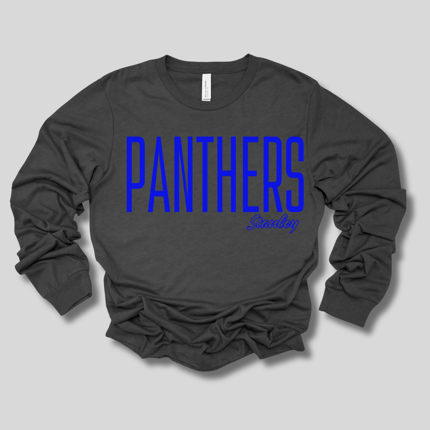 A dark charcoal gray long-sleeve t-shirt with a graphic design on the front, laid flat against a solid purple background. The design features the word 'BENTON' repeated in white outline text, overlaid with a purple and pink stylized 'Tigers' graphic.