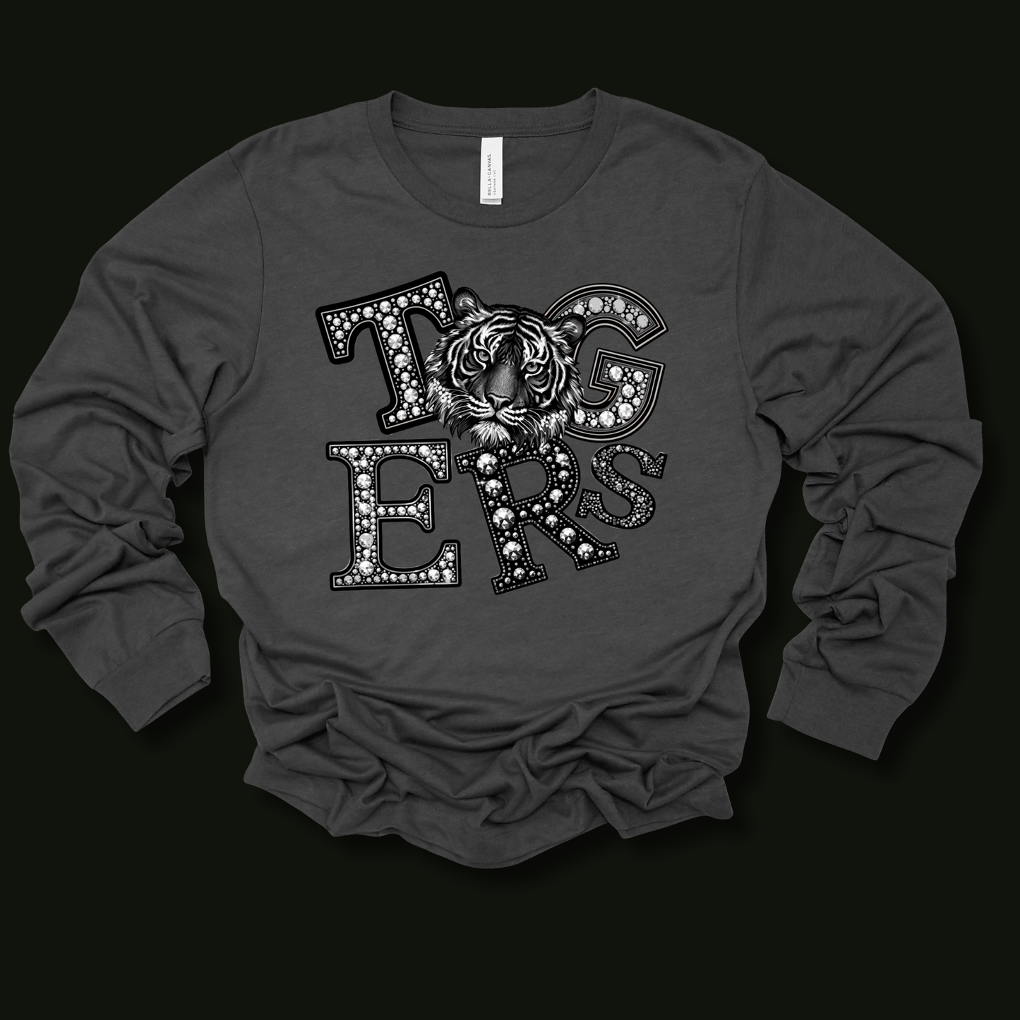 A dark gray long-sleeve t-shirt with a graphic print on the front featuring the word 'TIGERS' in decorative letters with a tiger face in the center, laid flat on a black background.