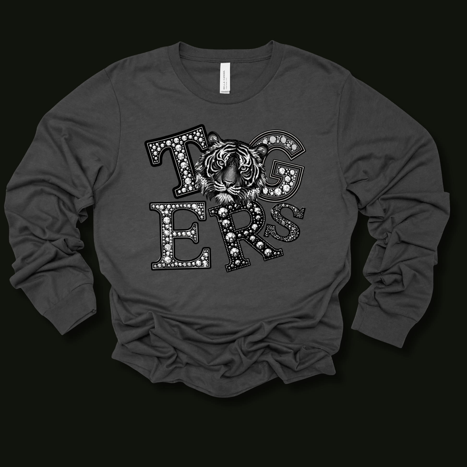 A dark gray long-sleeve t-shirt with a graphic print on the front featuring the word 'TIGERS' in decorative letters with a tiger face in the center, laid flat on a black background.