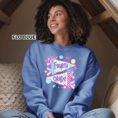 A woman wearing a light blue sweatshirt with a colorful 'Fourth Grade' banner graphic, sitting in a cozy indoor setting. The text 'FLO BLUE' is displayed on the left side of the image.
