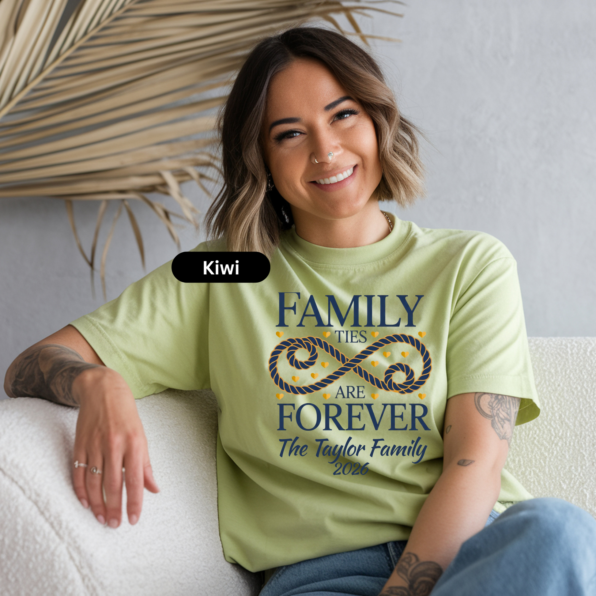 Woman wearing a light green t-shirt with 'Family ties are forever' design, sitting on a white couch.