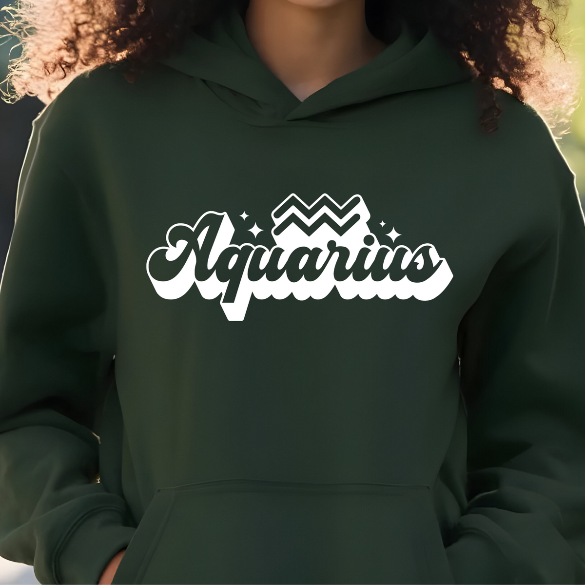 A person wearing a dark forest green hoodie with a white 'Aquarius' graphic printed across the chest, shown in a close-up shot.