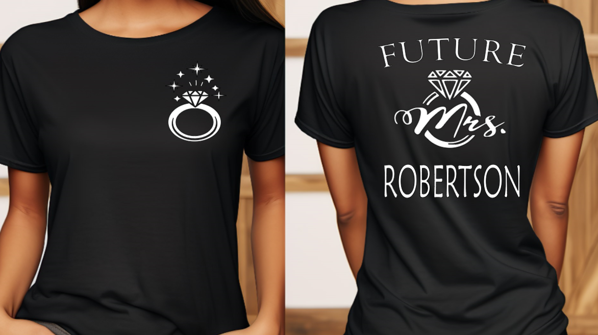 Woman wearing black shirt with FUTURE Mrs. on the back with bling ring on the front indicating engagement announcement shirt for bridal shower or engagement party and gift for new bride to be. 