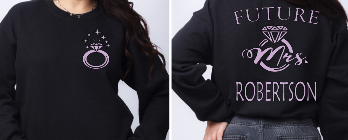 Woman wearing black sweater with FUTURE Mrs. on the back with bling ring on the front indicating engagement announcement shirt for bridal shower or engagement party and gift for new bride to be. 